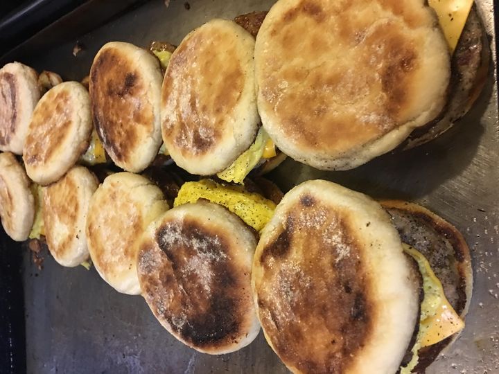 A grill full of English muffin breakfast sandwiches