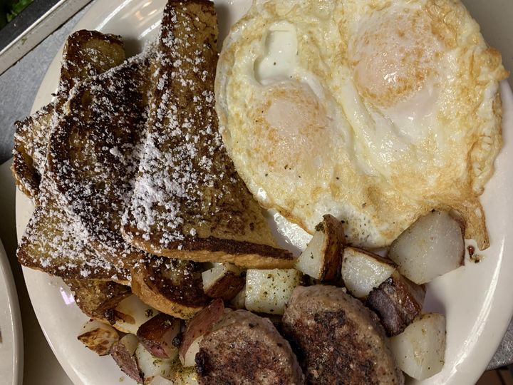 French toast with powdered sugar, two eggs, sausage patties and potatoes