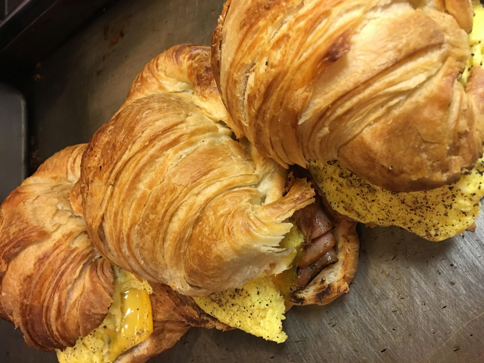 Croissant breakfast sandwiches stacked with egg, cheese and meat, fresh off the grill