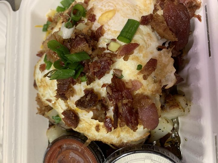 Country potatoes topped with eggs, crispy bacon and green onions