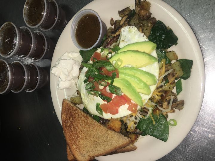 Potatoes with an over-easy egg, avocado, spinach, mushrooms and tomatoes, with wheat toast
