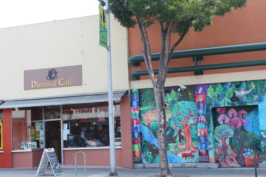 The Dimond Café storefront on Fruitvale Avenue, with its sign over the door and a colorful mural on the building next door